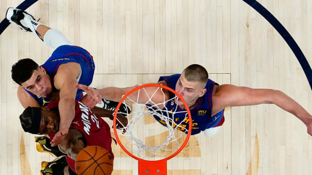 Miami Heat forward Jimmy Butler (22) shoots the ball against Denver Nuggets forward Michael Porter Jr. (top) and center Nikola Jokic (right) during the second half in game one of the 2023 NBA Finals.